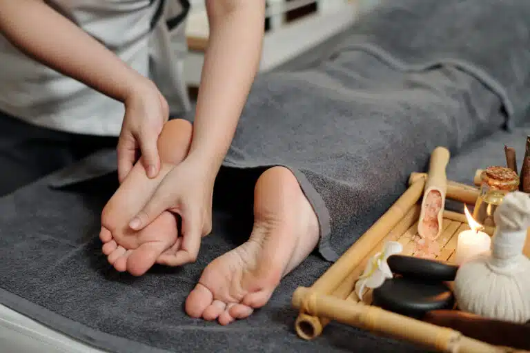 regular spa visits: Therapist performing a relaxing foot massage on a client at Apsara Spa, surrounded by spa essentials and soothing ambiance.