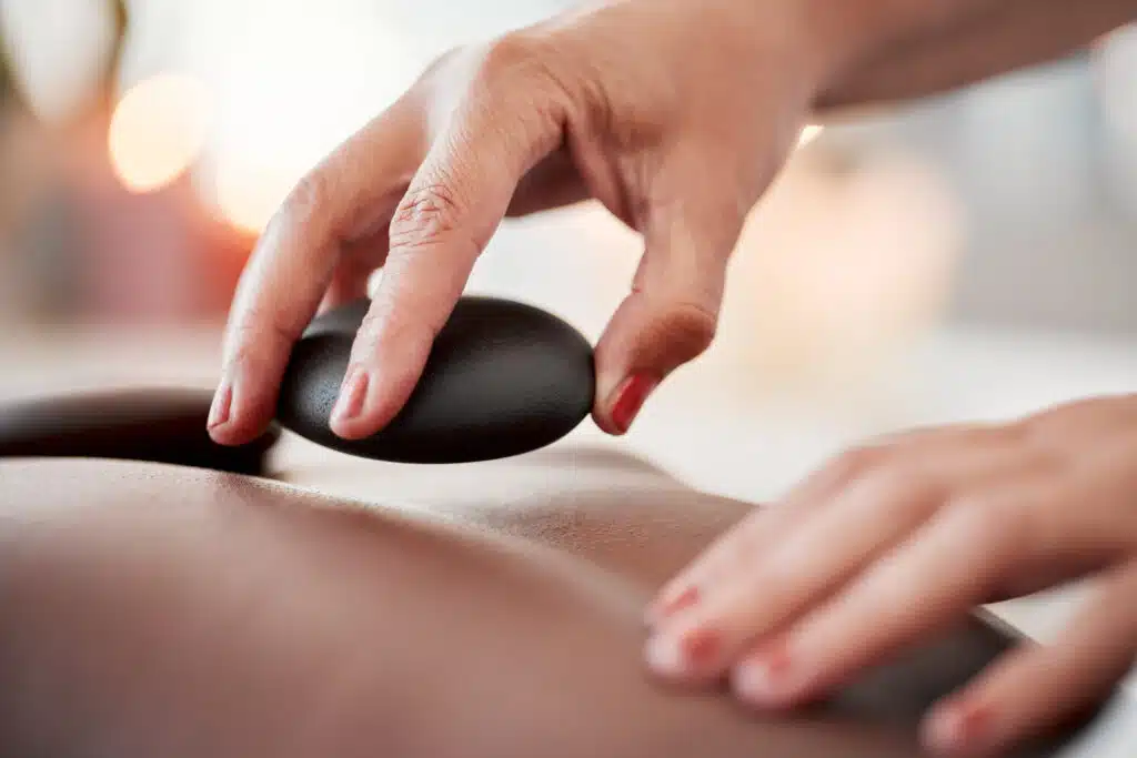 hot stone massage in Phuket: Hands placing hot stones on a client’s back at a Phuket spa.